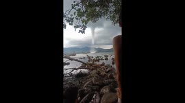 Thick waterspout tornado churns at sea during storm