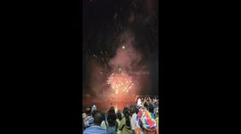 Fireworks display brightens up sky as illuminated boat floats along river for Buddhist festival