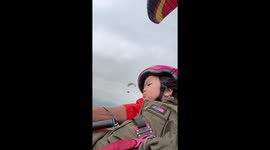 Toddler looks seriously unimpressed being taken on paramotor flight by her father