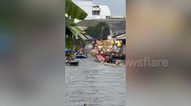 Devotees toss lotus flowers at Buddha statues being paraded on canal for religious festival