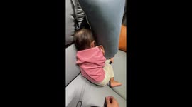 Toddler pushes parent's hand away while moping in sofa's corner
