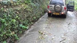 Storm Ciaran causes flooding , the rain is pouring over a slate wall and washing down a road causing flash flooding