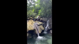 Tourist slips into water while clambering across wet rocks for a picture