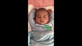 Baby charms parents as he smiles while sleeping