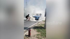 Men help each other extinguish fire on MINI Cooper car