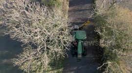 A tractor cuts hedges along flooded country lanes as fields to both sides are deep in flood water, Lullington Lane, East Sussex ,UK