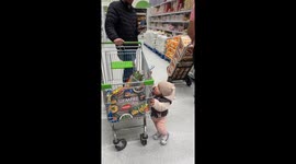 Toddler adds his favorite treats in shopping cart while dad's on phone