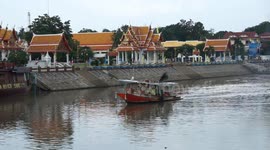 A small tug boat towing a number of large barges filled with sand on a river in Thailand.