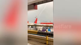 Thin waterspout tornado forms near ship during storm