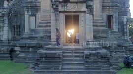 Golden sunrise beams through doorway of ancient Khmer temple in Thailand