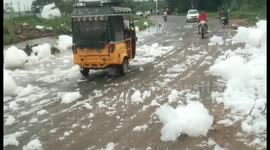 Road users navigate clouds of toxic foam overflowing from canal in Madurai, Tamil Nadu, amid heavy rain