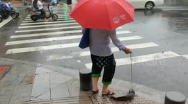 Elderly woman takes fish for a walk on wet road in China