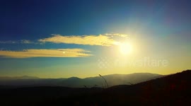 Time Lapse Sunset over a mountain. The sun and the moon