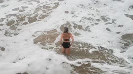 Cold sea swimming woman enjoying the health benefits of winter dipping in a cold ocean. Towan beach, Newquay, Cornwall UK