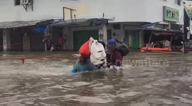 Rescuers help residents cross raging floods in the Philippines