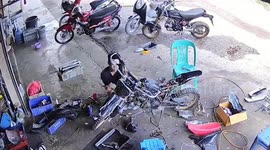 Snake slithers behind mechanic and hides under motorbike at shop