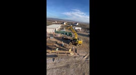 Daredevil worker swinging by the bucket of a construction site excavator *Unbelievable*