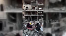 Gazan family sitting on the ruin of their house
