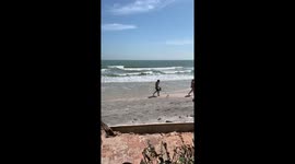 Thai man takes pet duck for a walk on beach