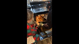 Excited couple feels the heat while taking Thanksgiving turkey out of oven