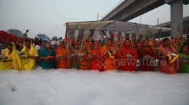 Devotees stand knee-deep in toxic foam whilst offering goods during Indian festival