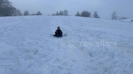 Young person sledging down a hill in Kendal enjoying the snow, whilst parts of Kendal and lake District are still recovering
