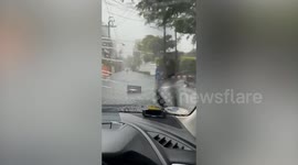 Cyclist removes trash bin swept into road by floods to help drivers