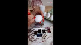 Artist hand paints an egg with beautiful floral pattern for Easter