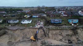 Demolition workers tear down the first of five clifftop homes in Hemsby, UK