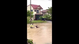 Motorcycle rider pushes his bike through flooded road