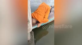 Monk rides boat through narrow gap under bridge to save puppy