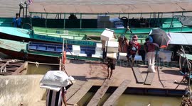 Boats being loaded on the Mekong River with goods from Thailand for Laos