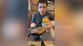 Hungry baby wets her lips as father savours fish dish