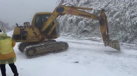 Excavator slides down icy slope narrowly avoiding crushing people to death