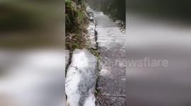 Hiker slips and slides down icy stairs while climbing down mountain