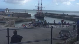 An old fashioned ship sails into a UK harbour
