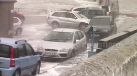 Cars inundated with water as storm waves crash over sea wall