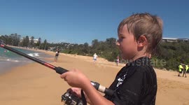 Young boy catches a fish at a beautiful beach