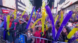 New Year’s Eve revelers dance and wave balloons in Times Square