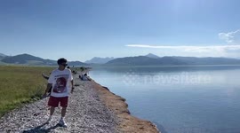 Boy makes skipping stones at Sayram Lake in China