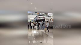 Two men holding giant car balloon trick people at mall into thinking it's real