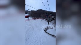 Snowboarder seen dangling from ski lift by his rucksack
