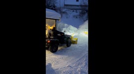 Man uses ATV with a massive snow blodet in the front to remove the snow