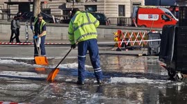 Workers assigned to break up frozen Trafalgar Square fountains as visitors enjoy icy scene