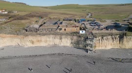 Excavator begins demolition work on former hotel on UK coast threatened by coastal erosion