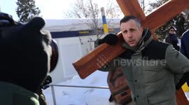 Christian farmer carries giant cross to gates of World Economic Forum conference in protest