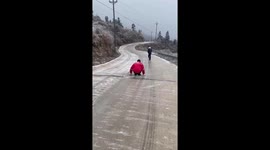 Kid slips over while sliding down icy road in China