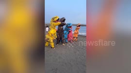 Beachgoers on dinosaur costumes race along beach in Taiwan