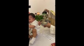 Adorable baby laughs as baptism water tickles his head