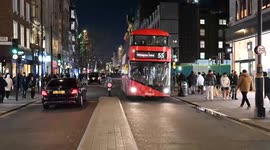 Red Bus driving along Oxford Street in the evening, London, United Kingdom